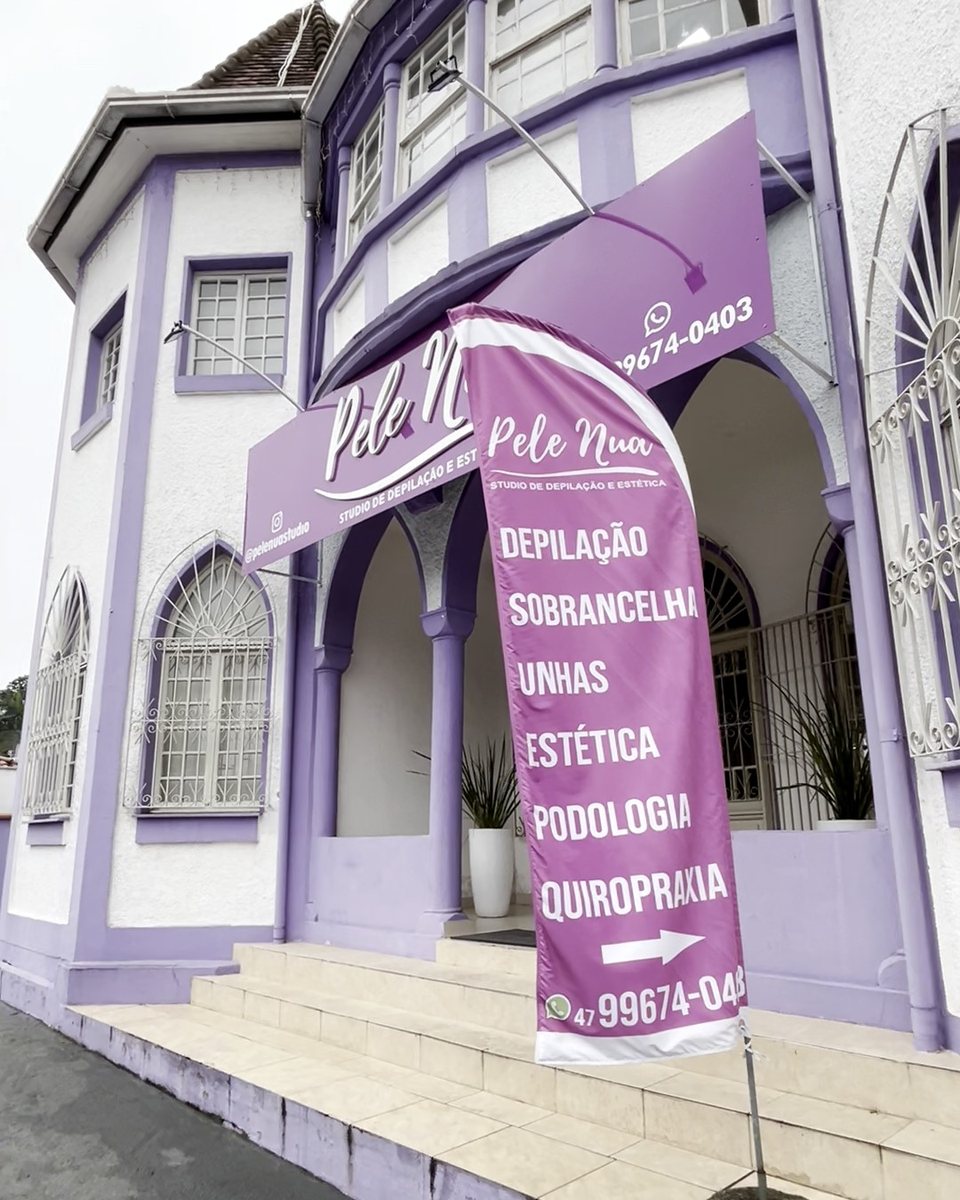 Fachada do prédio lilás do Studio Pele Nua, com a escada de entrada e a bandeira de podologia